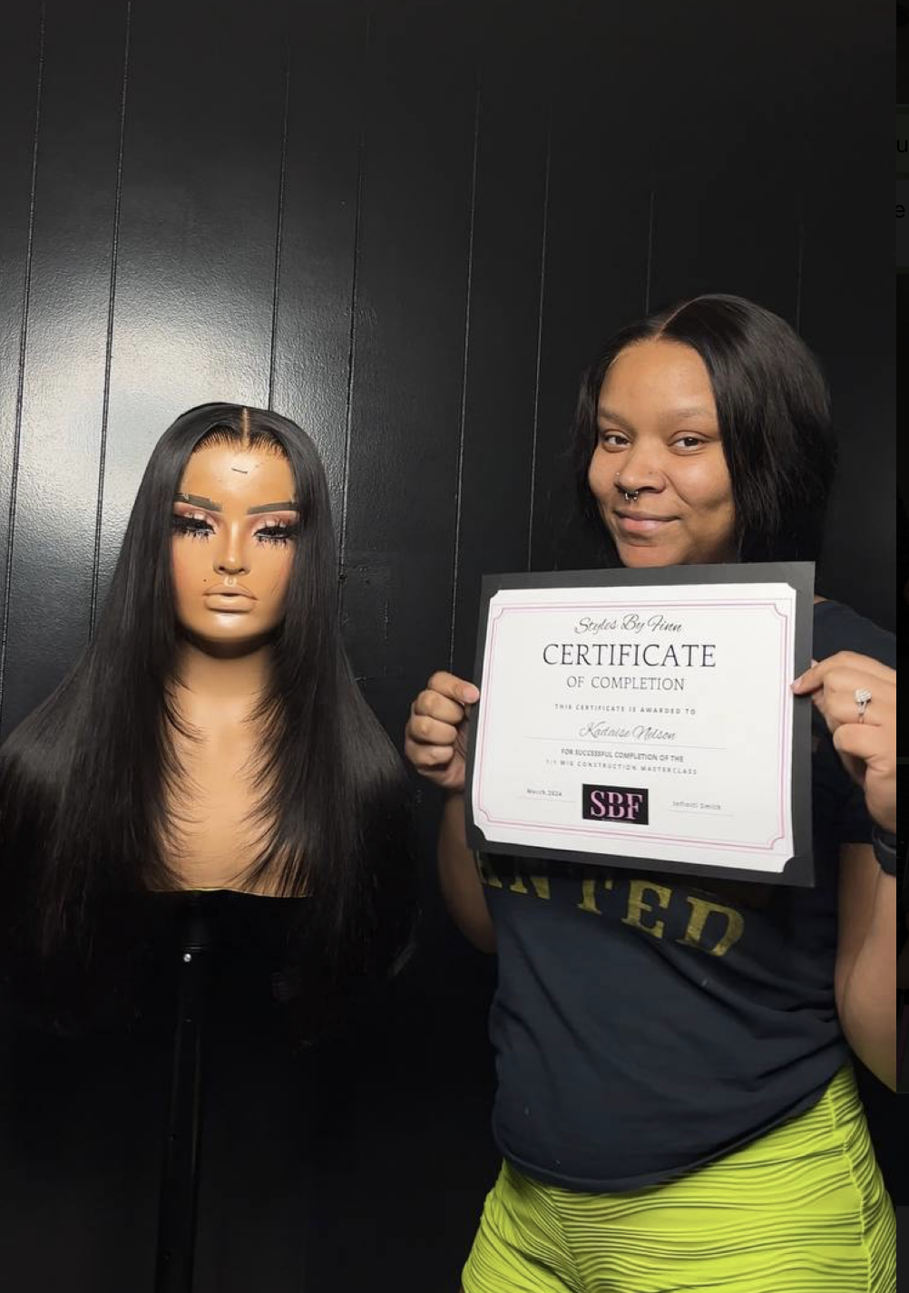 Graduate posing with completed wig and SBF certificate
